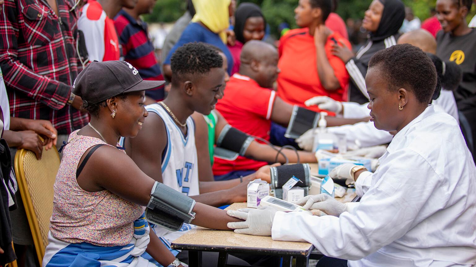 People sat at a table get vaccinated against Ebola as part of a community event.